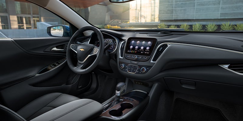 The interior of a Chevy Malibu, showing the black dashboard, steering wheel, infotainment screen, and center console.