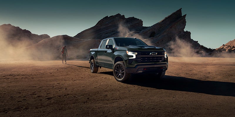 A dark green Chevrolet pickup truck parked on a desert landscape