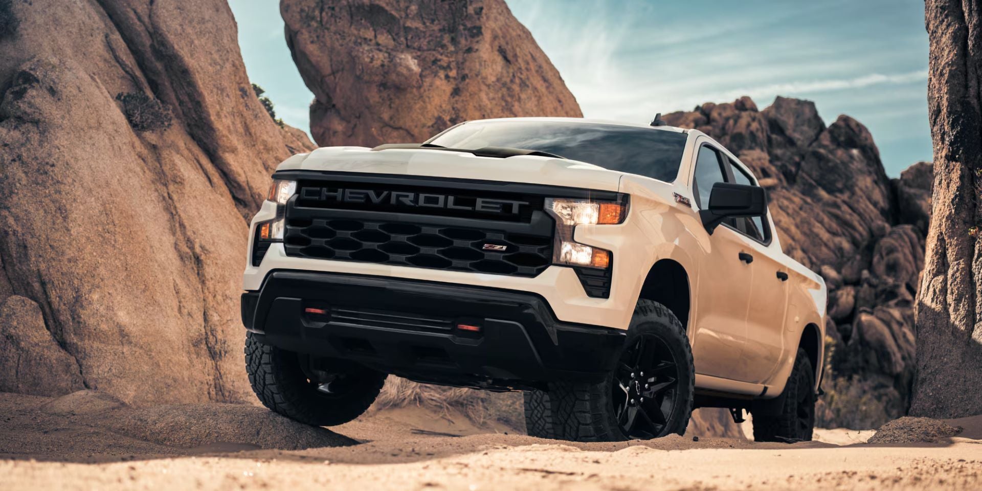 Beige Chevrolet pickup truck driving through a rocky off-road landscape