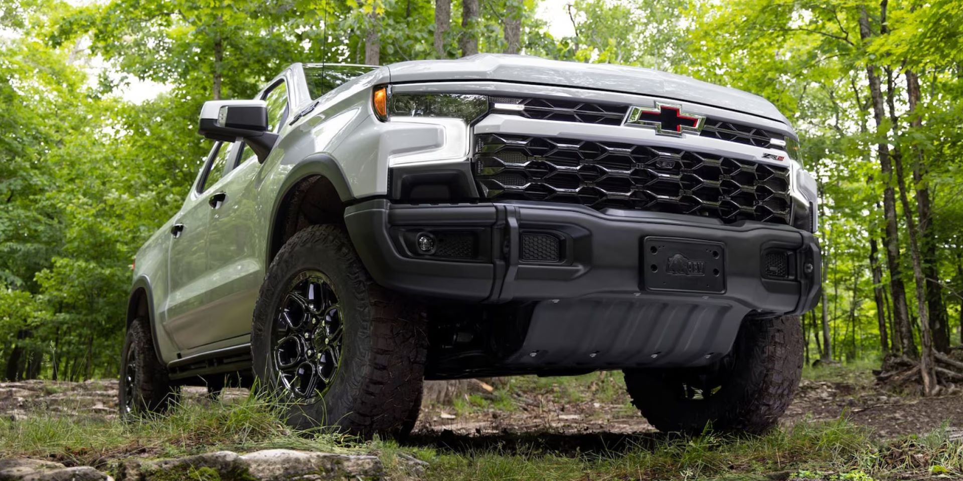 Green Chevrolet pickup truck driving on a forest trail