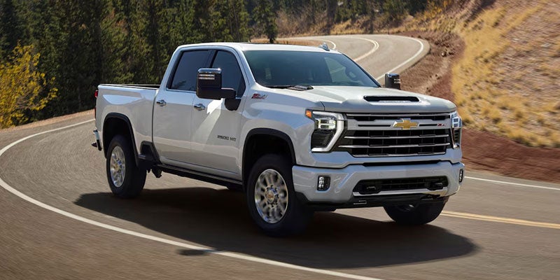 A white Chevrolet pickup truck driving on a winding paved road