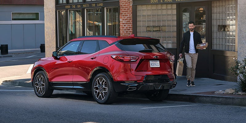 Rear three-quarter view of a red Chevrolet SUV parked along a city curb