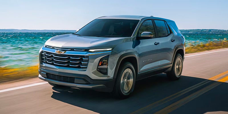Chevrolet Equinox EV driving on a coastal road showcasing front exterior design