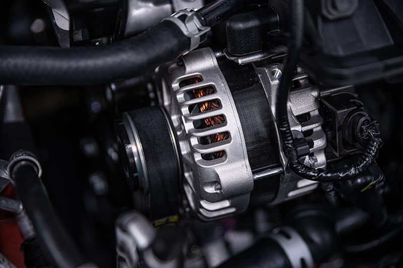 Close-up view of a car alternator and drive belt within an engine
