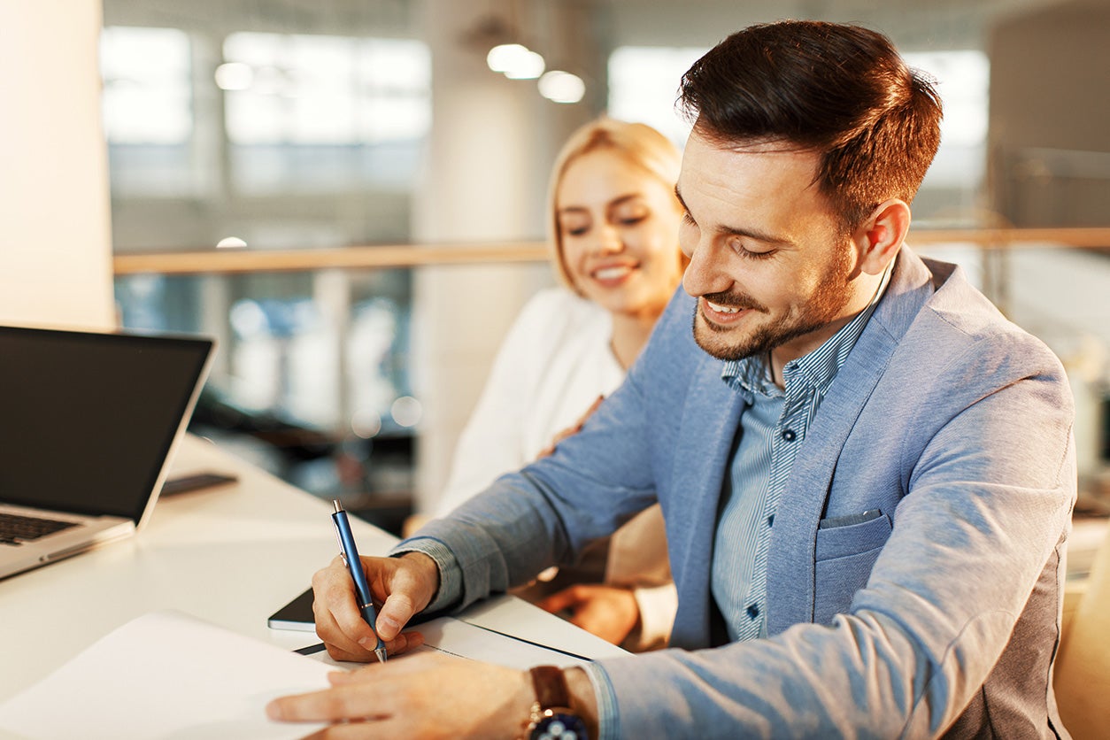 Customers completing car selling paperwork at dealership