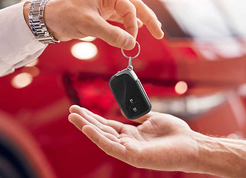 One person handing a car key fob to another person